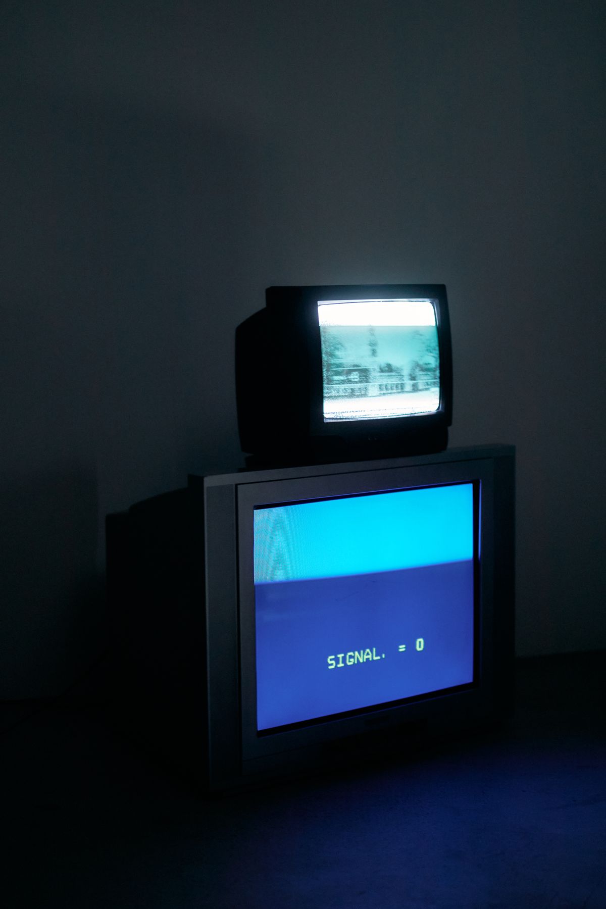 Two retro CRT monitors glowing blue in a dark room — the mood of watching something carefully