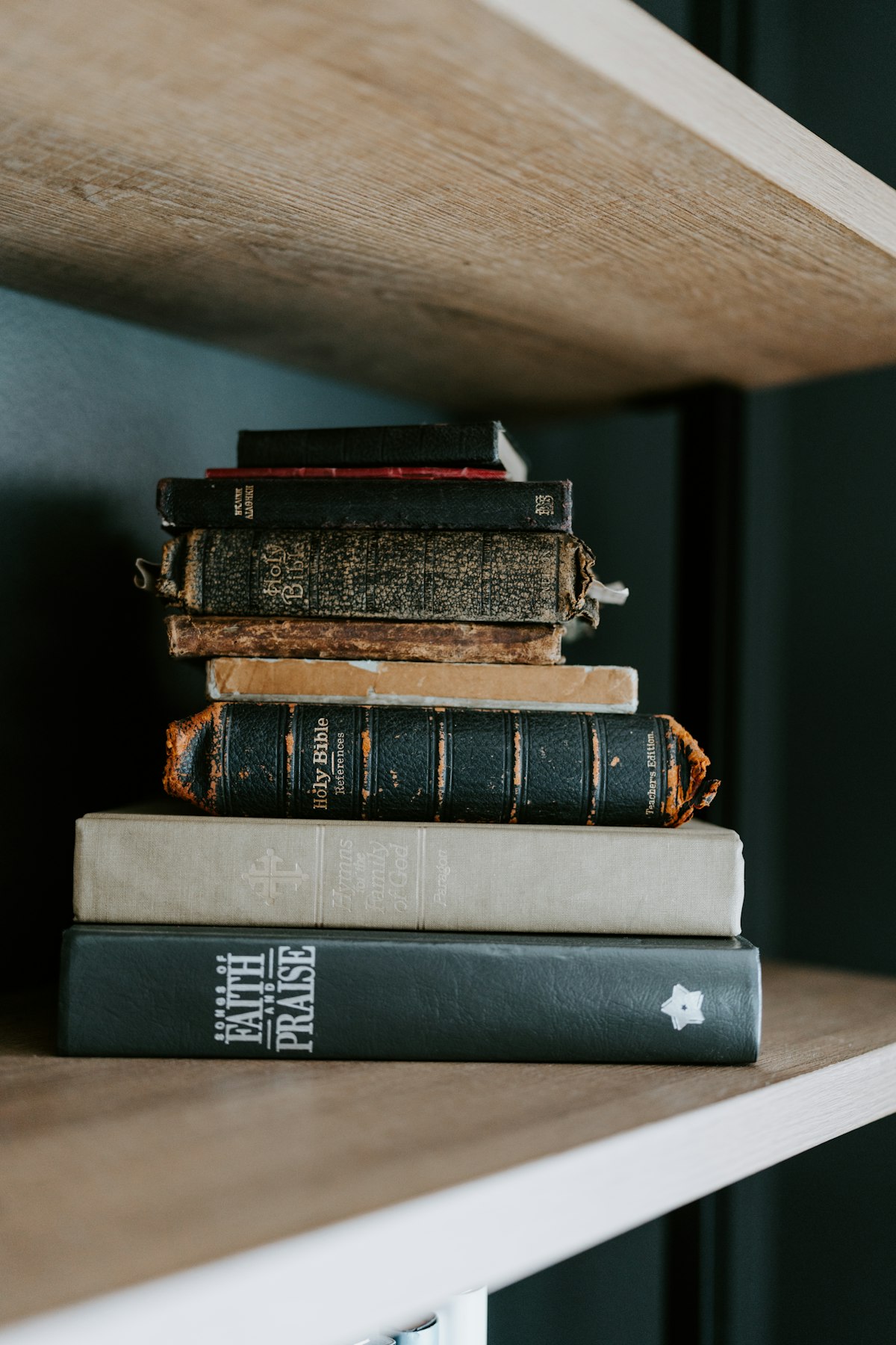 Stack of dark moody books on a wooden shelf — the quiet discovery of overlooked things